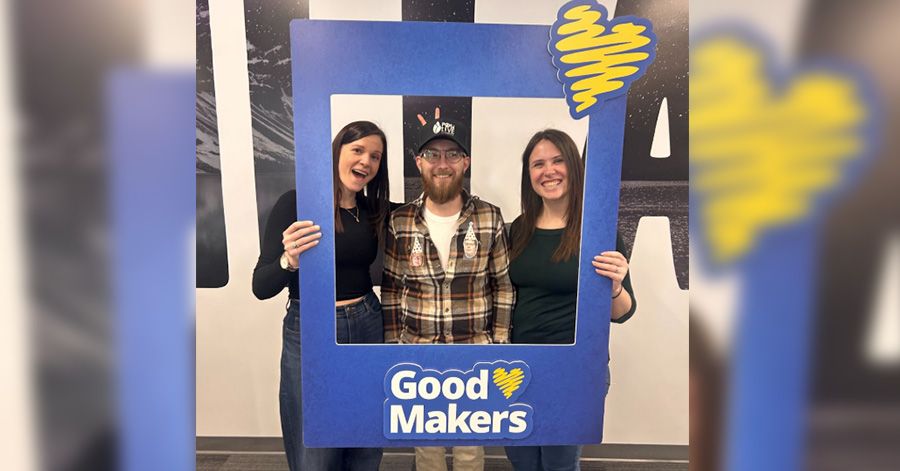 People pose for a photo within a GoodMakers frame.