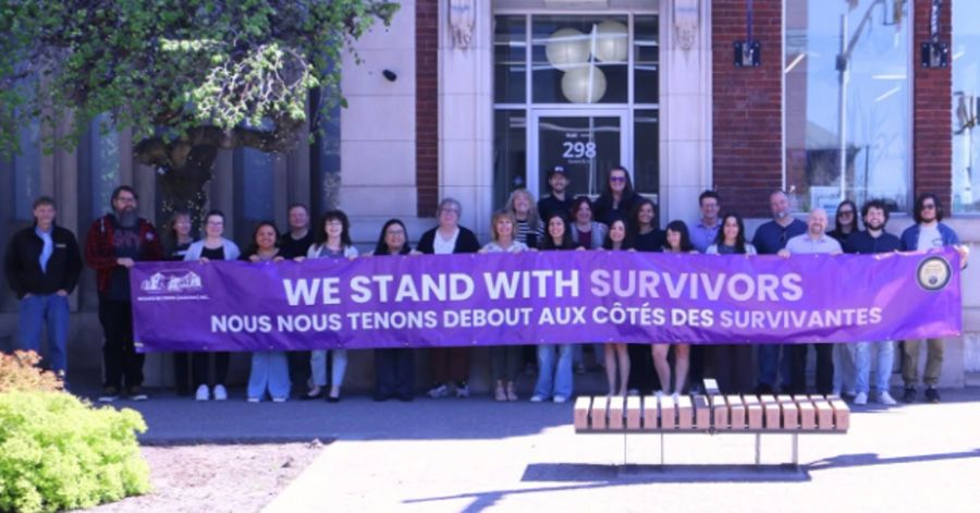 Village Media HQ staff holding 'We Stand With Survivors' sign