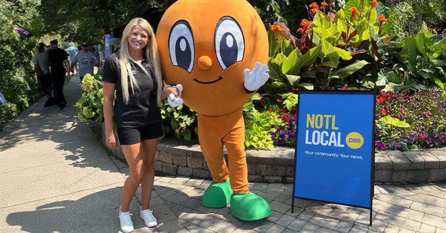 Lindsay Zdichavsky posing with a peach mascot