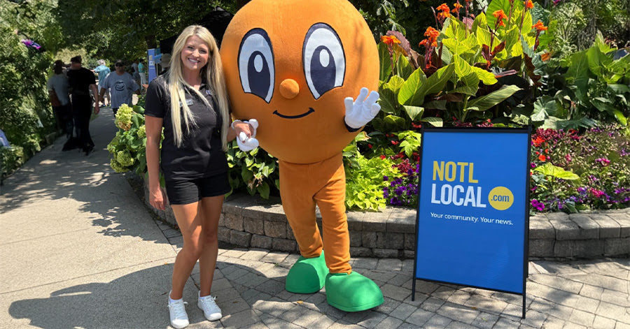 Lindsay Zdichavsky posing with a peach mascot