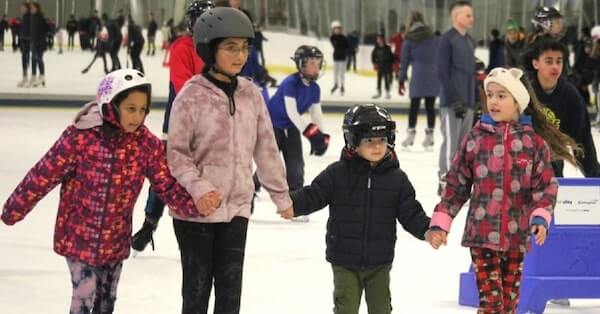 Amalia Moraru, Anna Moraru, Matei Deli and Nicole Deli hold hands during a free skate sponsored by BurlingtonToday